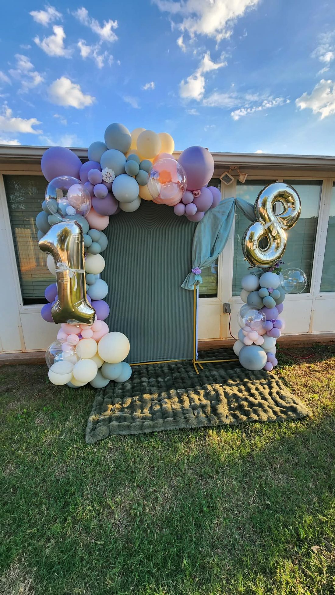 Outdoor pastel balloon arch with gold number balloons for an eighteenth birthday